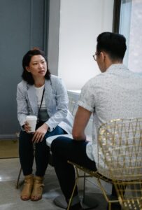 Two adults in their thirties having a relaxed conversation in a cafe, representing adult perspectives on the Rice Purity Test